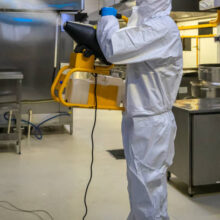 man in protective equipment disinfects with a spray gun industrial kitchen surfaces due to coronavirus covid-19 .Virus pandemic